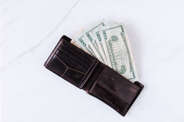 several one hundred dollar bills in a black leather wallet